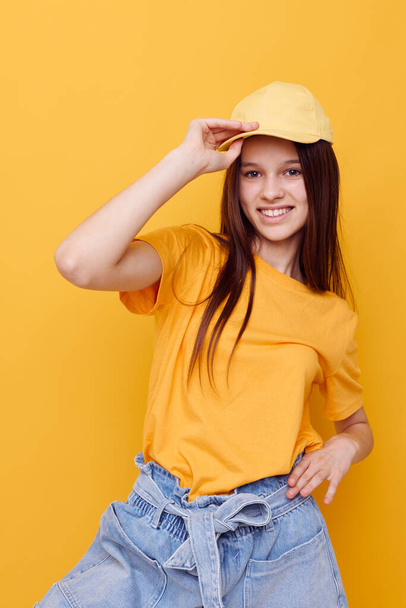 optimistic young woman posing in a yellow T-shirt and cap yellow background - Foto, Imagem