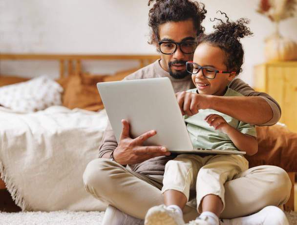 Feliz família afro-americana filhinho com o pai assistindo vídeos engraçados no laptop juntos em casa - Foto, Imagem