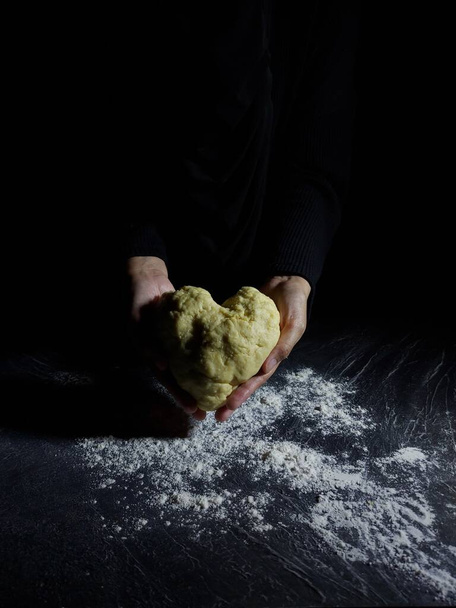 Ręka kobiety robi mąkę. Fotografia do pieczenia historii. Ciemny nastrój. - Zdjęcie, obraz