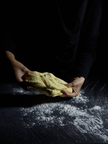 Ręka kobiety robi mąkę. Fotografia do pieczenia historii. Ciemny nastrój. - Zdjęcie, obraz
