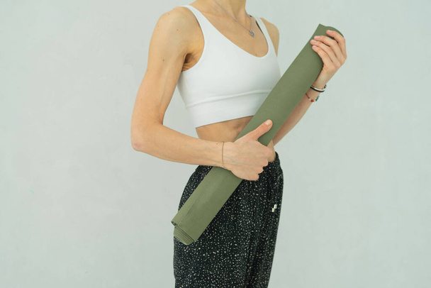 grüne Yogamatte in den Händen einer Frau - Foto, Bild