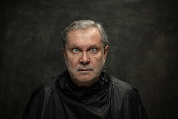 Portrait of angry senior man looking at camera isolated on dark vintage background. Concept of emotions, fashion, beauty, self-reinvention - Fotó, kép