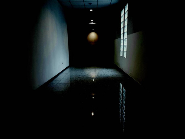 Uma grande janela em um corredor escuro com paredes brancas - Foto, Imagem