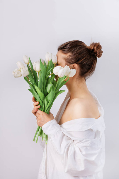 Mujer bonita sosteniendo ramo de tulipanes blancos. Flores de primavera tulipán. - Foto, Imagen