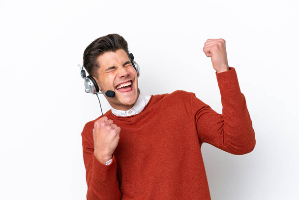 Telemarketer caucasian man working with a headset isolated on white background celebrating a victory - Foto, Bild