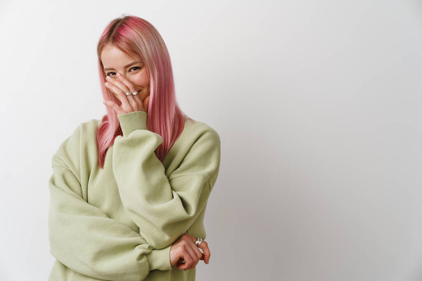 Young white woman with pink hair smiling and covering her face isolated over white background - Fotó, kép