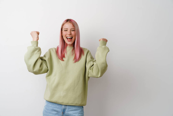 Young excited woman screaming and making winner gesture isolated over white background - Foto, afbeelding