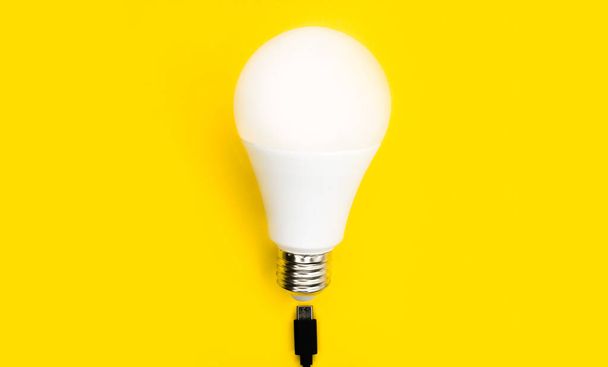 A glowing light bulb. Mockup. Empty space. Beautiful colors. Bright yellow background. Light bulb for advertising. - Zdjęcie, obraz