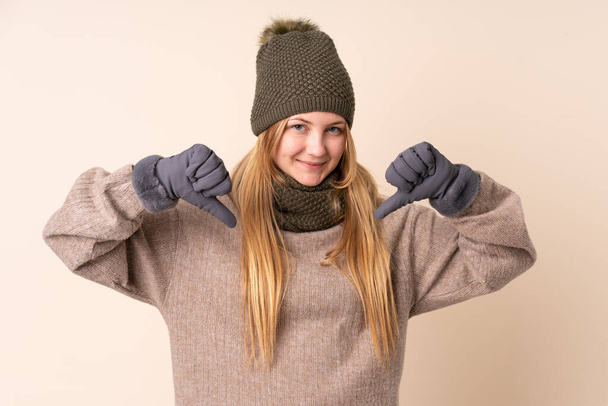 Έφηβη Ουκρανή με χειμερινό καπέλο απομονωμένη σε μπεζ φόντο περήφανη και αυτάρεσκη - Φωτογραφία, εικόνα
