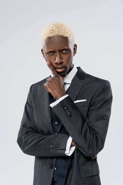 blonde and serious african american man with blue eyes isolated on grey  - Photo, Image