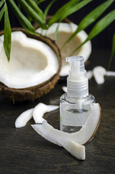 Coconut oil for hair in a bottle with a dispenser on a dark background - Foto, Bild