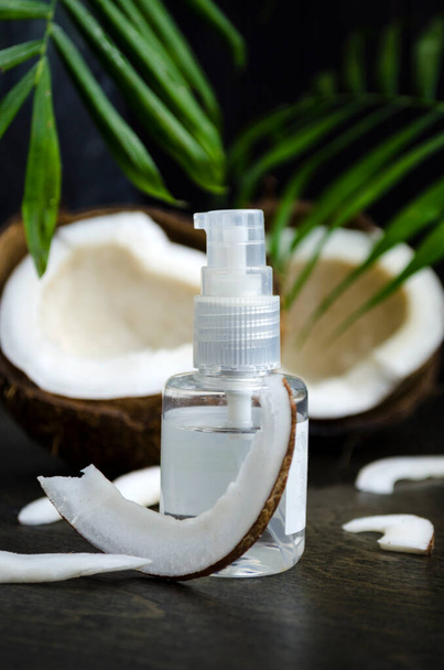 Coconut oil for hair in a bottle with a dispenser on a dark background - Fotografie, Obrázek