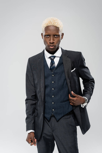 elegant african american man in formal wear posing isolated on grey - 写真・画像