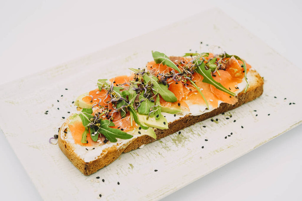 Smoked salmon toast, fresh cheese, avocado and arugula - Photo, image