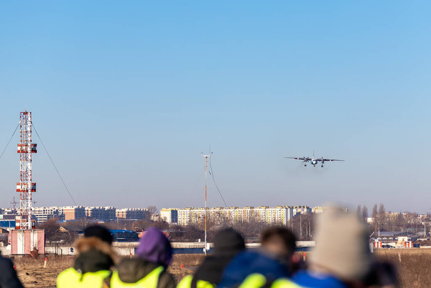 Ομάδα πολλών ανθρώπων που παρακολουθούν αεροπλάνα που προσγειώνονται και απογειώνονται διάδρομο αεροδρομίου planespotting συνέδριο ζεστό πρωινό χρόνο. Αεροπλανοφόρα με γιλέκο ασφαλείας σε αναμονή άφιξη Aicraft πλησιάζει αναχώρηση - Φωτογραφία, εικόνα