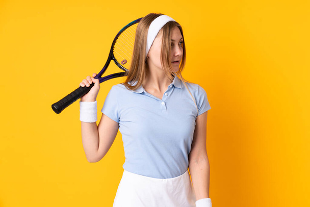 Teenager Ουκρανή τενίστρια απομονωμένη σε κίτρινο φόντο παίζοντας τένις - Φωτογραφία, εικόνα