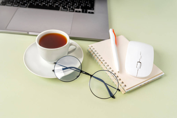 Escritorio de oficina verde claro, escritorio de estilo minimalista con teclado, taza de té y vasos, espacio para copiar, vista superior, diseño plano, diseño - Foto, Imagen
