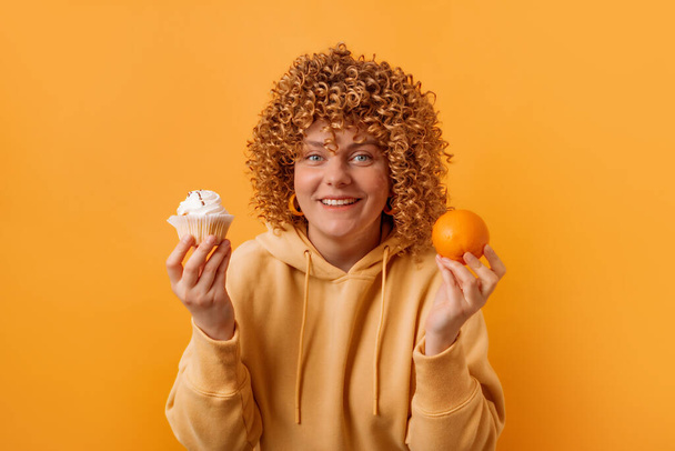 Gyönyörű nő nyár friss teljes narancs és édes torta elszigetelt sárga háttérrel. Egészséges étel jó ízlés. - Fotó, kép