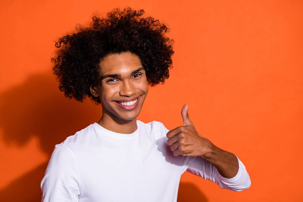 Photo of pretty charming guy wear white shirt showing thumb up empty space isolated orange color background - Photo, image