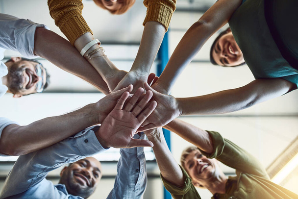 Η ομάδα υποστήριξης είναι δυνατή ομάδα. Χαμηλή γωνία βολής μιας ομάδας συναδέλφων που ενώνουν τα χέρια τους στην αλληλεγγύη κατά την εργασία. - Φωτογραφία, εικόνα