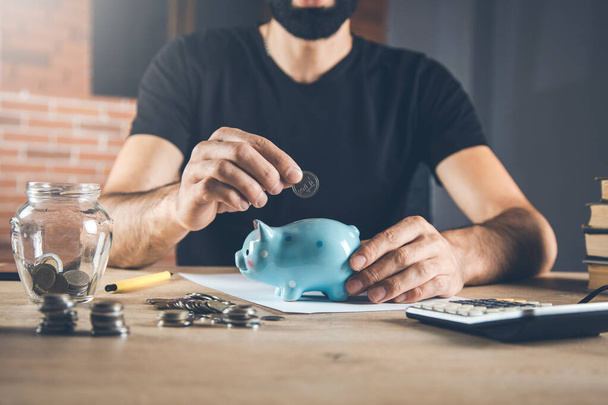 man hand piggy bank with coin on desk - Foto, Bild
