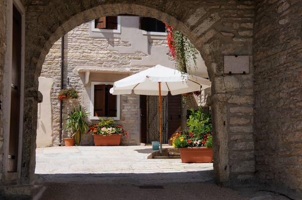 Un bonito patio con sombrilla, flores de colores y puertas de madera
, - Foto, Imagen