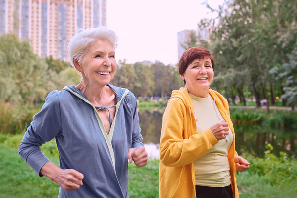 twee volwassen vrouwen joggen in het park. gezond leefstijlconcept - Foto, afbeelding