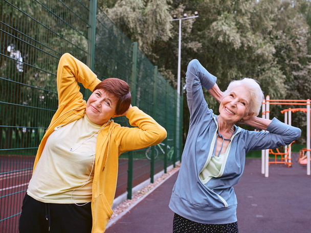two mature women doing sport exercises in the park. healthy lifestyle concept - Photo, Image
