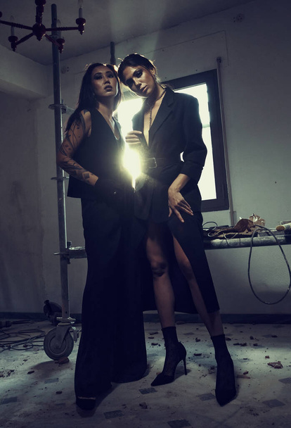 Two women wear elegant fashion clothes posing indoor. Fashion and beauty concept - Φωτογραφία, εικόνα