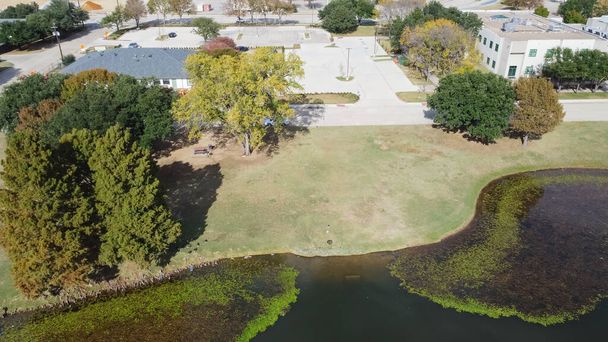 Office building and commercial warehouse near algae blanket lily pad pond in Carrollton Texas, USA. Aerial view mixed use zoning with facility service building, purchasing, transportation - Photo, Image