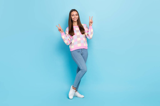 Photo of cheerful friendly lady show two v-signs wear sweater jeans sneakers isolated blue color background - Фото, изображение