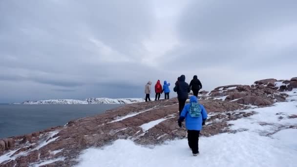 A Barents-tenger partján február végén. Teriberka, Oroszország. A turisták hegyet másznak. - Felvétel, videó