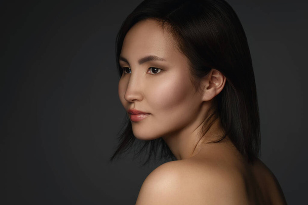 Portrait of young and beautiful asian woman with a short dark hair on gray background - Foto, Imagem