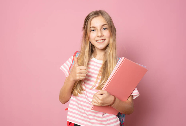 Menina bonita nova usando mochila estudante mostrando polegar de pé isolado sobre fundo rosa. Conceito de educação. - Foto, Imagem