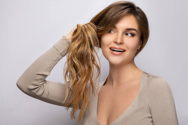 Young woman is happy with her beautiful and healthy hair on gray background - Fotografie, Obrázek