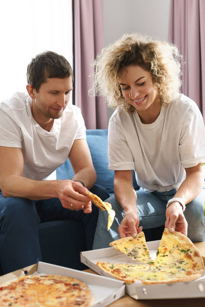 Happy and hungry couple eating delicious pizza at home - Valokuva, kuva