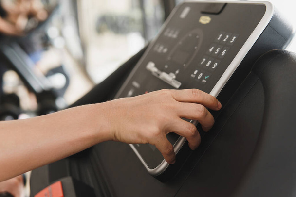 Closeup of female hand changing settings on a treadmill in a gym - Fotografie, Obrázek