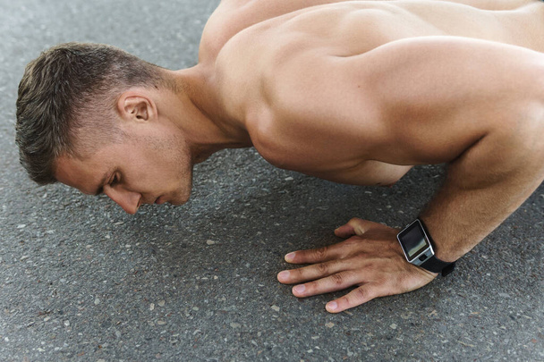 Young and muscular man is doing push-ups during calisthenic workout on a street - Fotografie, Obrázek