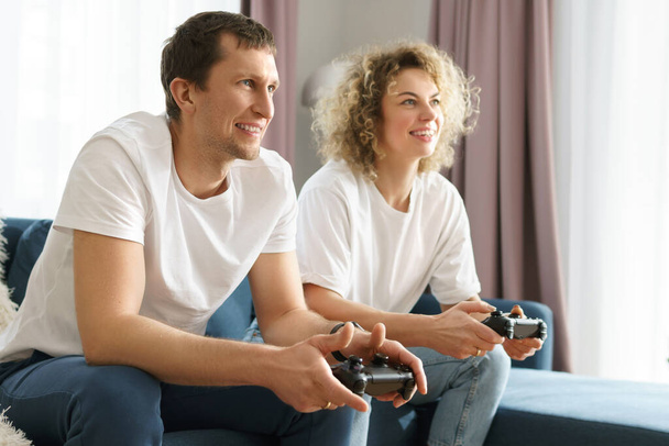 Young happy couple with a gamepads are playing video game console - Fotografie, Obrázek