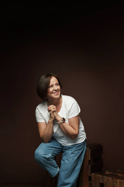 Portrait d'une belle femme d'âge moyen posant dans un studio sur fond brun - Photo, image