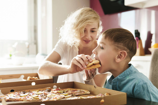 Mother and her cute son eating delicious Italian pizza at home - Zdjęcie, obraz