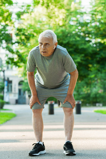 Exhausted elderly man after his jogging workout in a city park - Photo, image