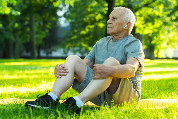 Calm elderly man relaxing  in green city park after his workout - Fotoğraf, Görsel
