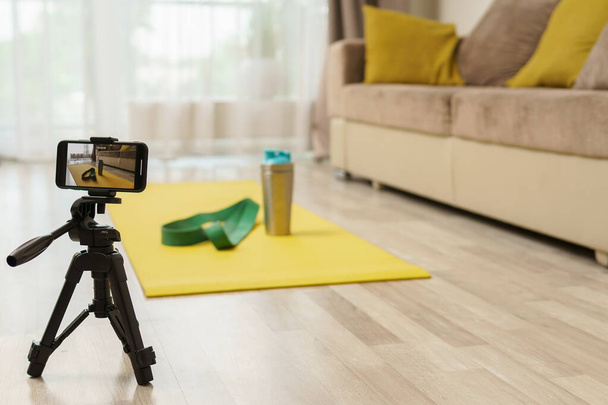 Smartphone on a tripod recording video with a equipment for home workout. Concepts of online fitness training or vlogging. - Fotografie, Obrázek