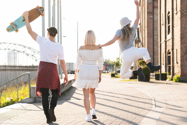Enjoying freedom. Three happy teenage friends are walking in a city.  - Фото, зображення