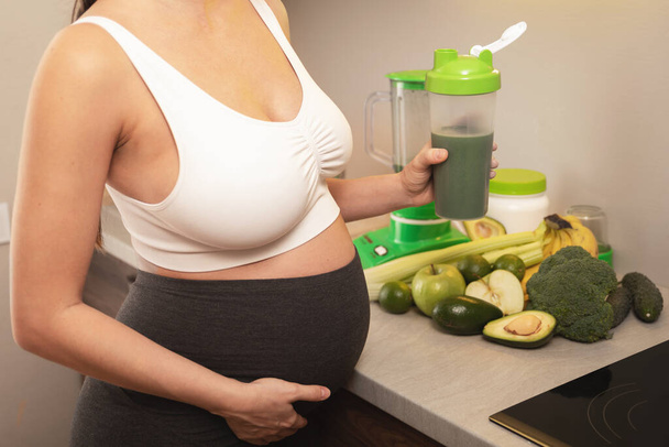 Young pregnant woman holding shaker with a green protein cocktail - Foto, Imagem