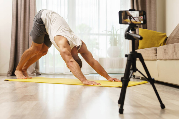 Fitness blogger is streaming or recording video for his subscribers during his home workout - Foto, Imagem