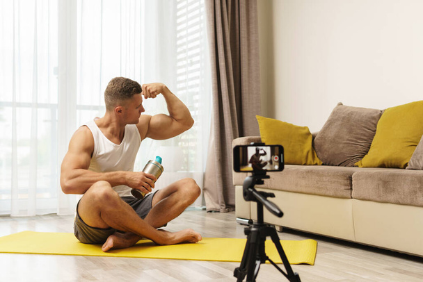 Fitness blogger at home is streaming or recording video for his subscribers - 写真・画像