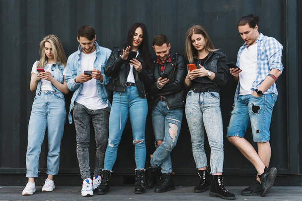 Skupina mladých a stylových přátel používající smartphony pro zasílání zpráv místo skutečné komunikace - Fotografie, Obrázek