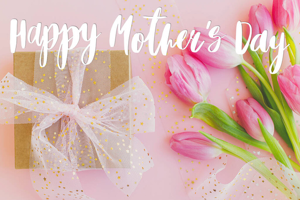 Happy Mother Day Text auf rosa Tulpenstrauß und Geschenkbox auf rosa Hintergrund. Stilvolle Grußkarte. Happy Mother 's Day, Dankbarkeit und Liebe zu Mama. Handschriftlicher Schriftzug - Foto, Bild